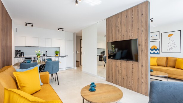 Uma sala de estar moderna com sofá, mesa de centro e painel para TV.