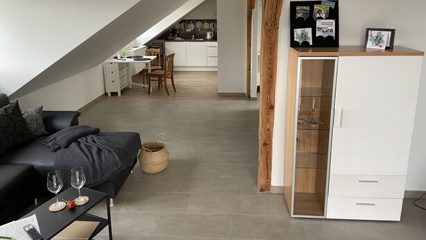 Un loft moderno con comedor, cocina y sala de estar con un sofá y dos copas de vino.