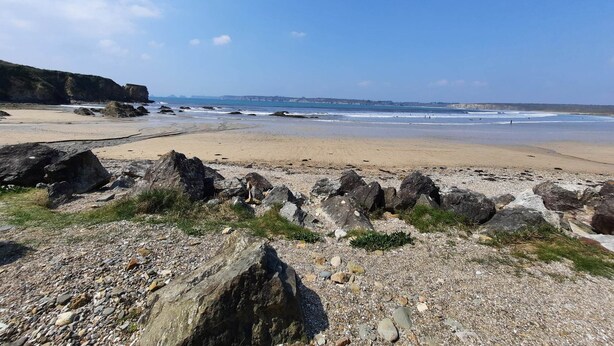 Een strand met een rotsachtige voorgrond en een helder uitzicht op de oceaan.