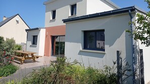 Een modern huis met twee verdiepingen, een terras, een schotelantenne en een kleine tuin.
