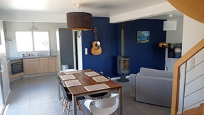 Een moderne keuken met houten kasten, een inbouwoven en een eethoek met een houten tafel en witte stoelen.