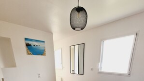 Een slaapkamer met een groot bed, een raam, een schilderij en een hanglamp.