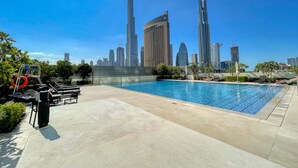 A rooftop pool with a city skyline in the background. - Maison Privee - Luxury Apt with Burj Khalifa Vw & Direct Mall Access (Dubai)