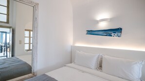 Una camera d'albergo con un letto, uno specchio grande e un quadro raffigurante una veduta costiera.