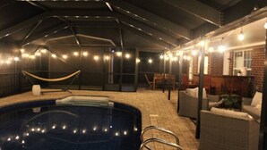 Indendørs swimmingpool med hængekøje, liggestole og lyskæder.