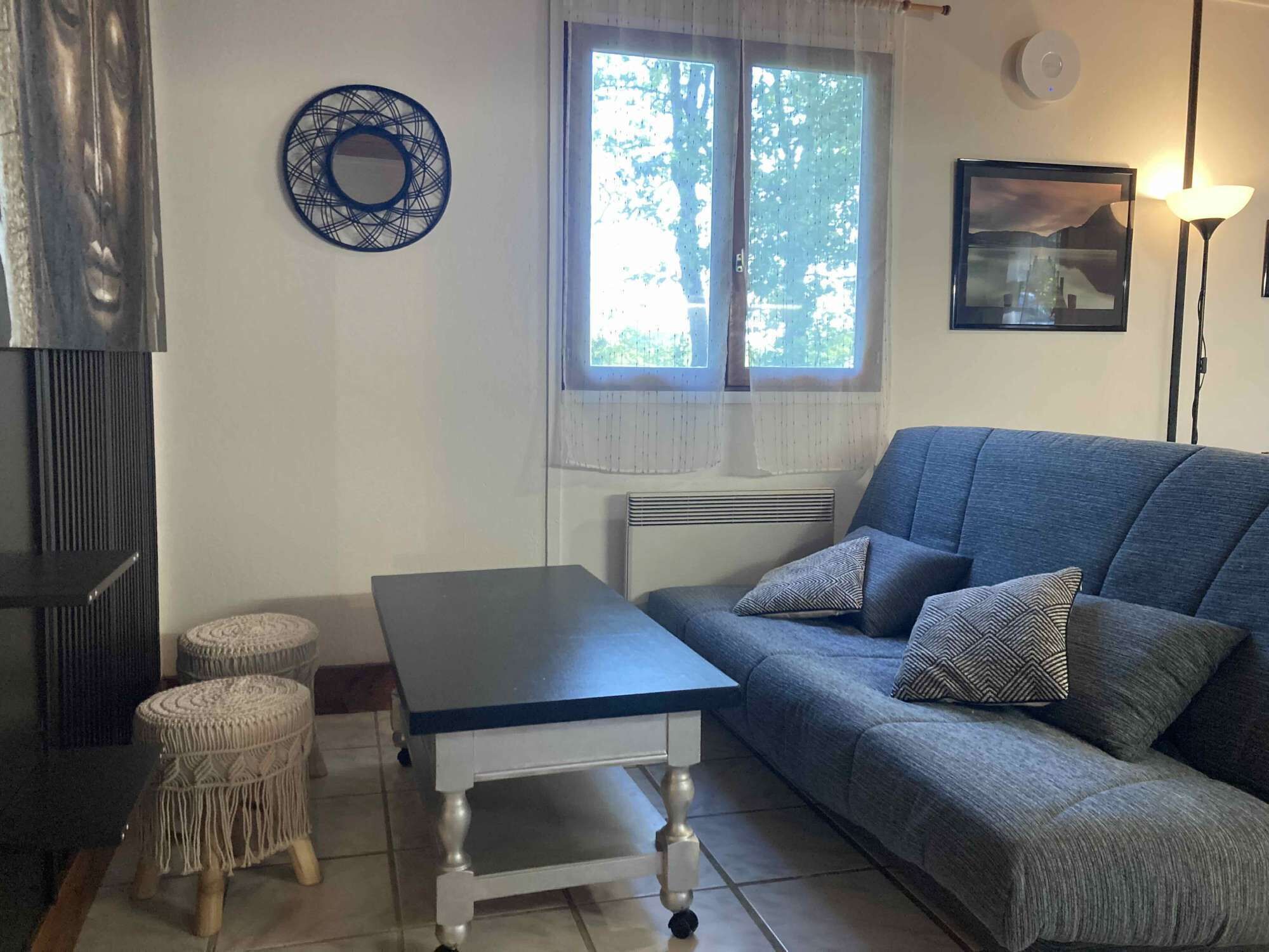 Een woonkamer met een bank, een tafel en twee macramé zitjes.