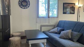 Een woonkamer met een bank, een tafel en twee macramé zitjes.