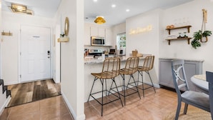Une cuisine moderne dotée d’un coin bar, avec un néon, des tabourets de bar en osier et une petite table à manger.