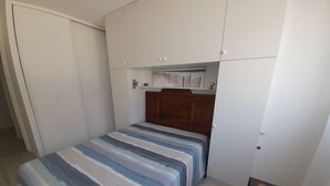A bedroom with a bed, a wooden headboard, a wardrobe, and a small table. - Arcachon: Central T2, Close to Casino, Beach & Shops, Private Parking (Arcachon)