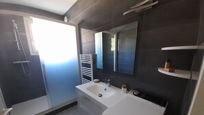 A modern bathroom with a large mirror, a white sink, and a shower area. - Arcachon: Central T2, Close to Casino, Beach & Shops, Private Parking (Arcachon)