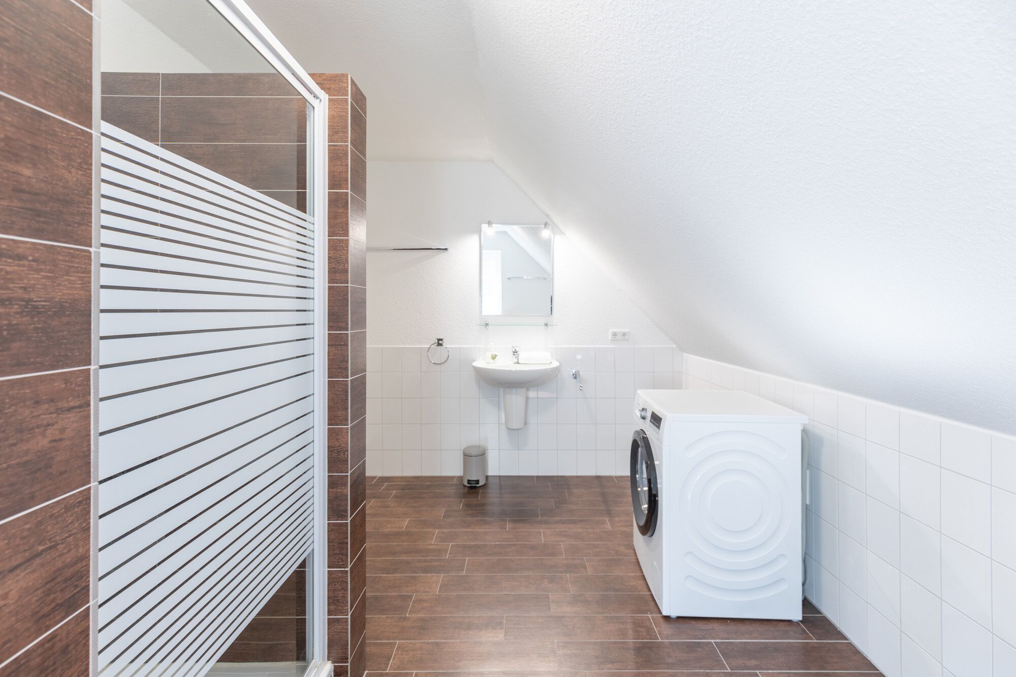 Un baño moderno y compacto, con lavadora integrada, un lavabo y un espejo.