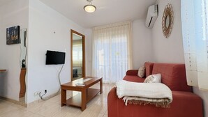 Een woonkamer met een rode bank, een houten salontafel, een flatscreen televisie en een grote spiegel.