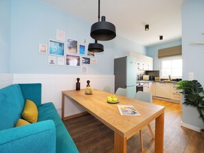 Et moderne køkken med et træbord, en teal farvet sofa og et spiseområde.