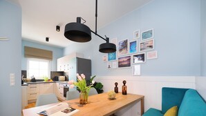Une cuisine moderne avec des meubles blancs, une table à manger en bois et un canapé de couleur turquoise.