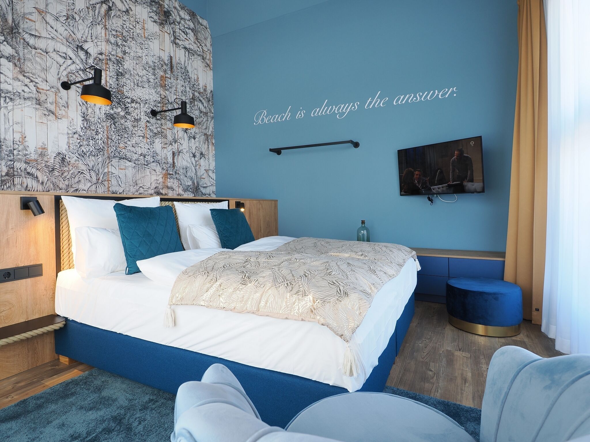 Un dormitorio moderno con una cama grande, un televisor montado en la pared y un mural decorativo.