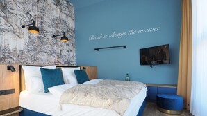 Ein modernes Schlafzimmer mit einem großen Bett, einem wandmontierten Fernseher und einem dekorativen Wandbild.