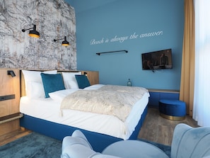 A modern bedroom with a large bed, a wall-mounted TV, and a decorative wall mural.