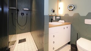 Un bagno moderno con doccia vetrata, lavabo con specchio e toilette.
