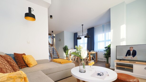 Een moderne woonkamer met een bank, een ronde salontafel en een televisie.