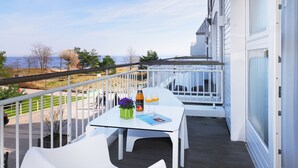 Ein Balkon mit einem weißen Tisch, zwei weißen Stühlen, einer Weinflasche und zwei Gläsern Orangensaft.