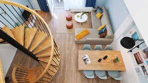 Ein modernes Interieur mit einer Wendeltreppe, einer Sofagarnitur, einem Esstisch und Blick ins Freie.