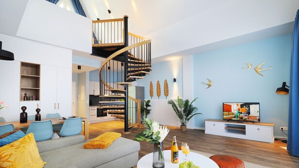 Ein modernes Wohnzimmer mit Wendeltreppe, Essbereich und Fernseher.
