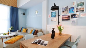 Ein modernes Wohnzimmer mit einem Holzespeisetisch, hellblauen Wänden und verschiedenen gerahmten Bildern.