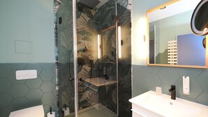 A modern bathroom with a glass-enclosed shower, a white toilet, and a white sink with a mirror above it. - 1-room vacation apartment with balcony (Seebad Heringsdorf)