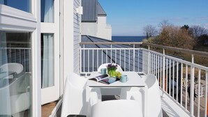 Een balkon met een tafel voor twee, uitkijkend op een wateroppervlak.