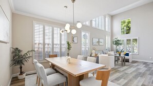 A spacious living room with a large wooden dining table, white sofas, and a chandelier. - 5BR Home Modern & Spacious for Business & Family (San Jose)