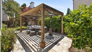 A covered patio area with a wooden pergola, outdoor seating, and a stone pathway. - 5BR Home Modern & Spacious for Business & Family (San Jose)