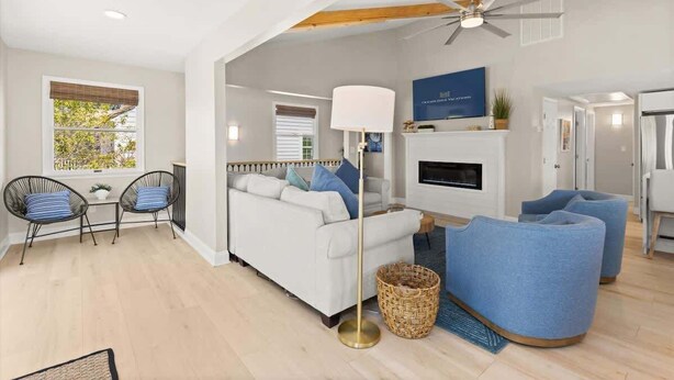 A modern living room with a white sofa, blue armchairs, a floor lamp, and a ceiling fan. - Fenwick Shores House II (Selbyville)