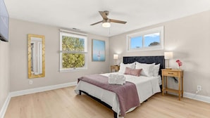A bedroom with a bed, two bedside tables, a ceiling fan, and two windows. - Fenwick Shores House II (Selbyville)