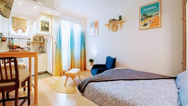Ein gemütliches Zimmer mit einem Bett, einem Schreibtisch und einem Sessel. An den Wänden sind Dekorationen und ein Fenster mit Vorhängen.