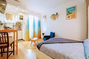 A cozy room with a bed, a desk, and a chair. There are wall decorations and a window with curtains.