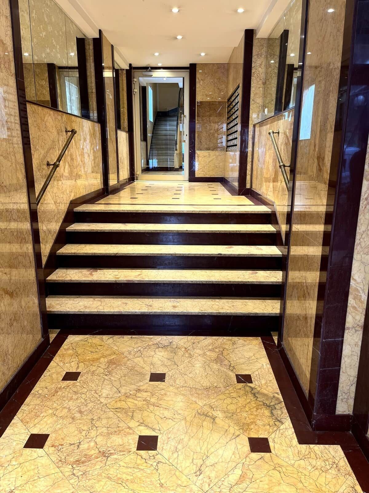 A marble staircase with handrails leading to an elevator.