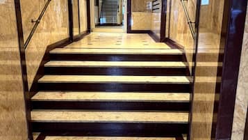 A marble staircase with handrails leading to an elevator.