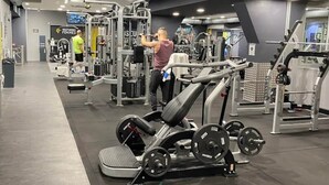 Ein Fitnessstudio mit verschiedenen Trainingsgeräten, darunter eine Hantelbank und Gewichtsmaschinen.