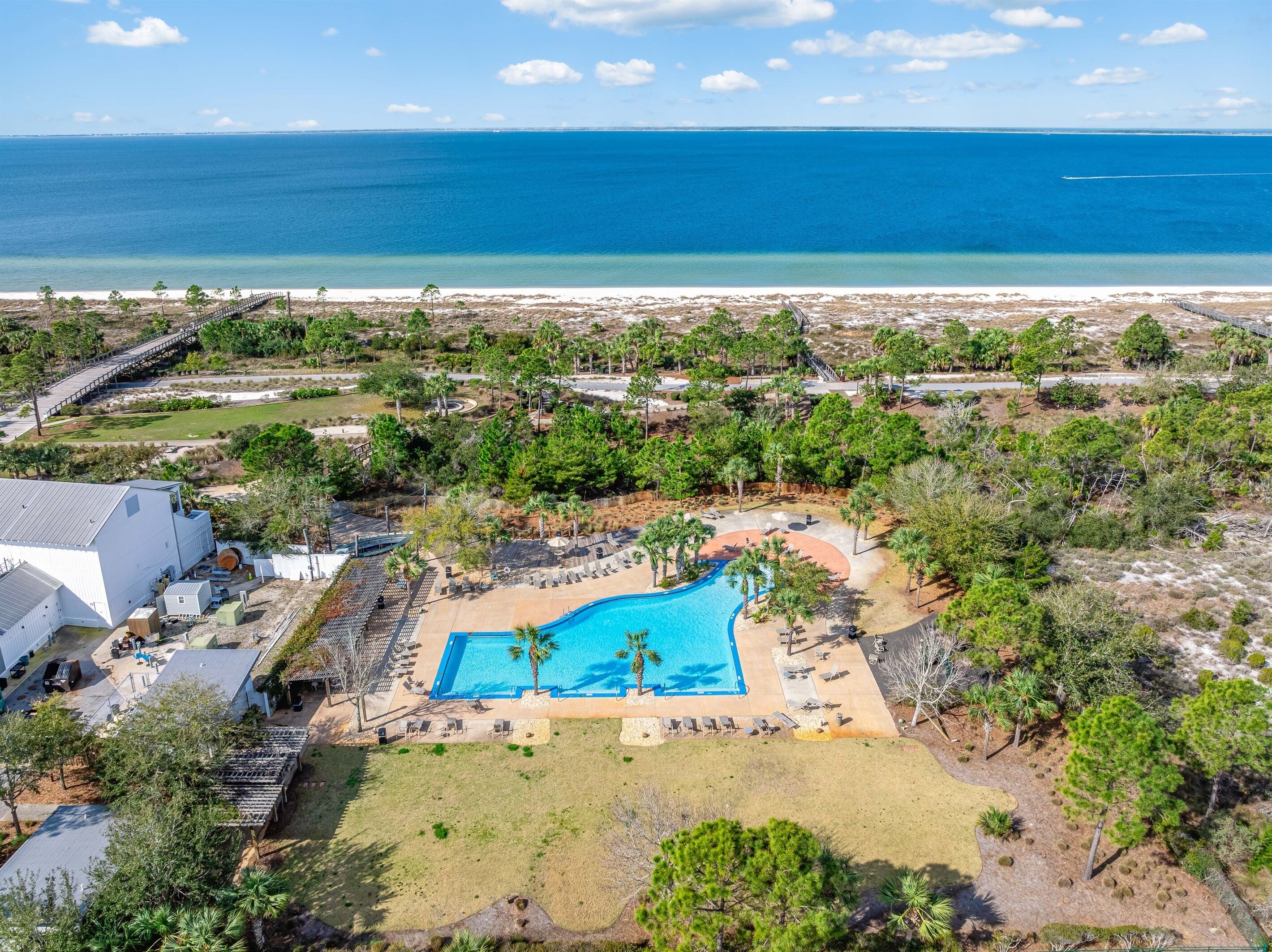 Vue aérienne d’un complexe hôtelier doté d’une piscine, d’espaces de détente et d’une plage.