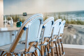 Wicker chairs with a checkered pattern, a bar area with a counter, and a view of the ocean. - HEATED Pool | Walk to Beach | Golf Cart | 3 King Beds | Amazing Sunset 🔆 (Port St. Joe)