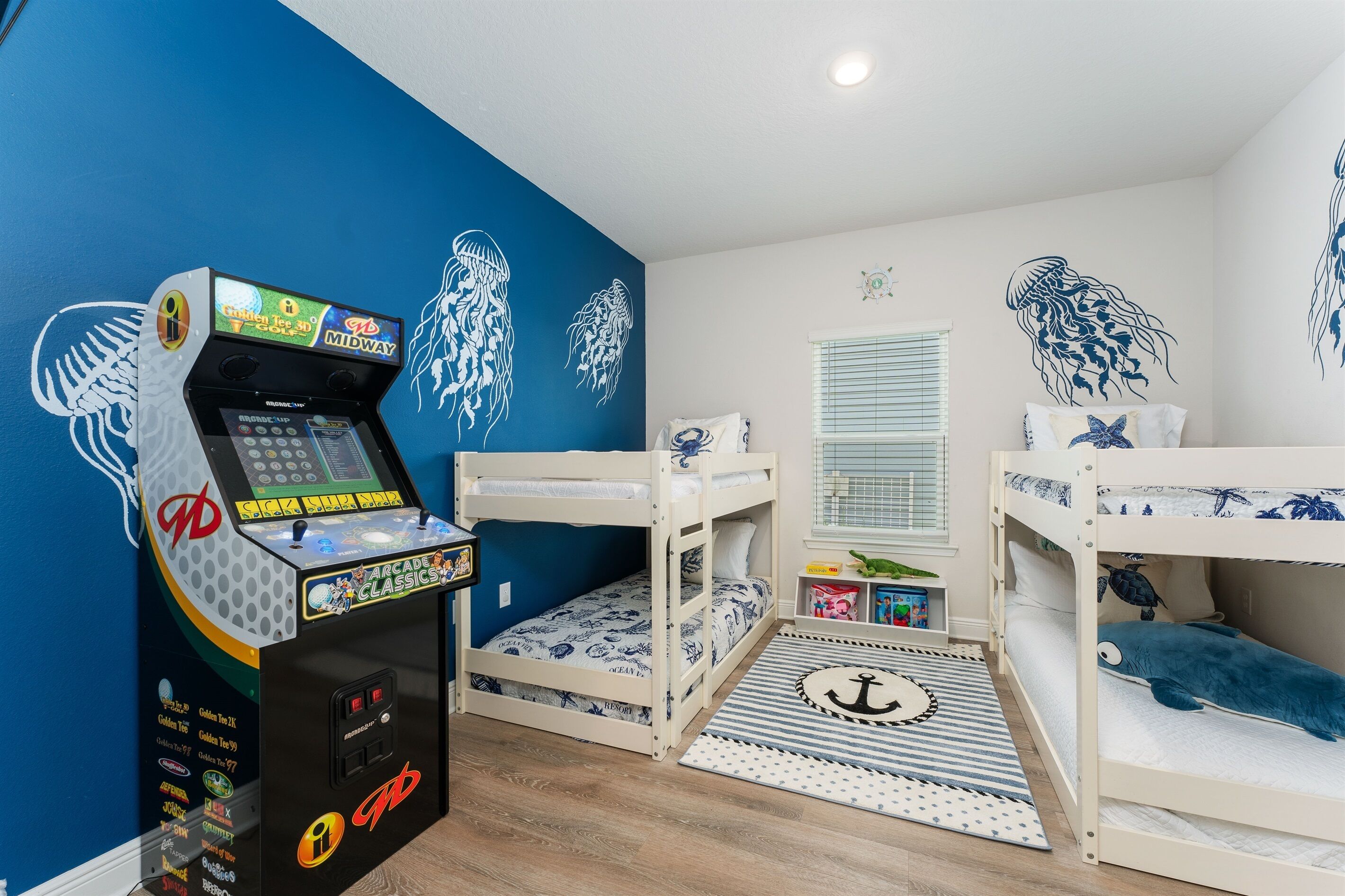 Une chambre d’enfant avec des lits superposés, une console de jeux et des décorations murales.