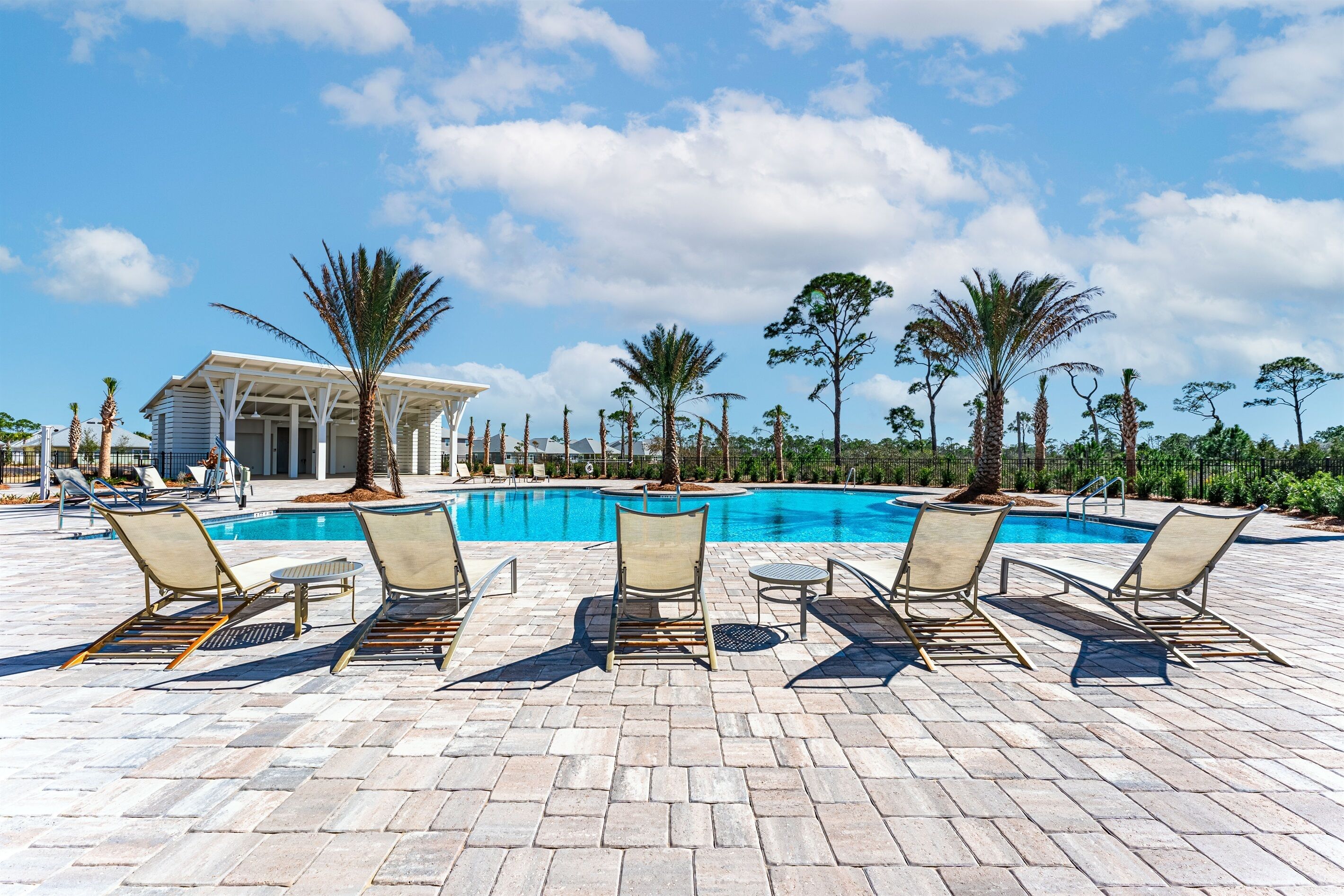 A pool area with lounge chairs and a covered pavilion.