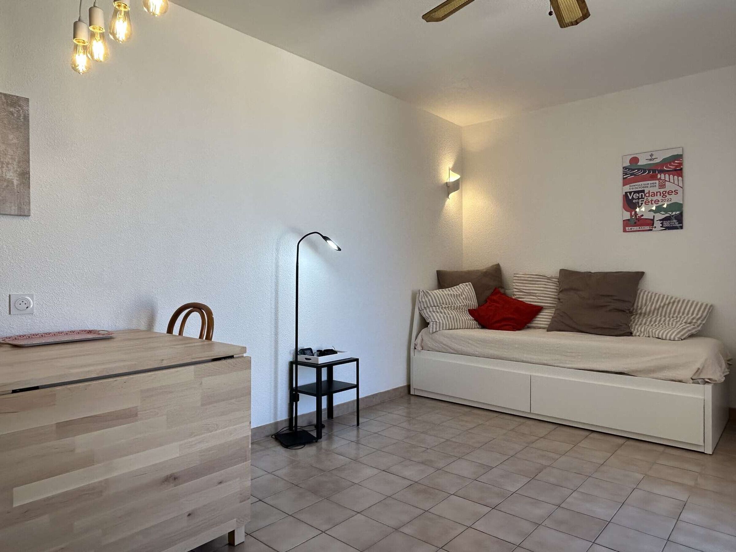 Ein minimalistisches Wohnzimmer mit einem Bett, einem Schreibtisch und einer Stehlampe.