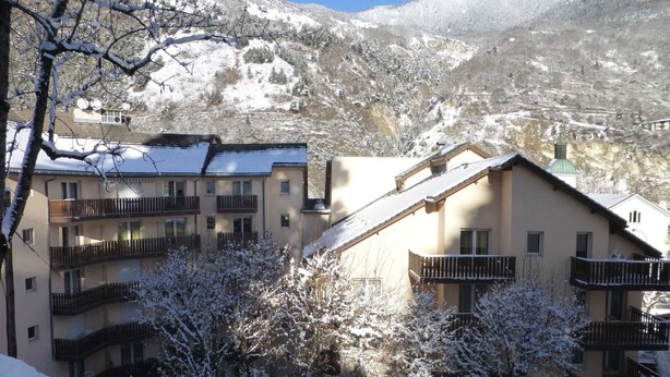 A snow-covered mountain town with multi-story buildings, balconies, and a clear sky.