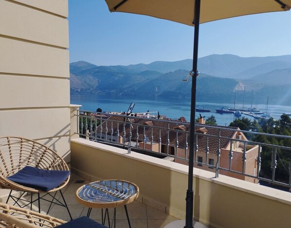 Un balcon donnant sur un port, avec des fauteuils en osier et une table.
