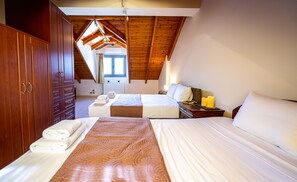 Une chambre avec deux lits, une armoire en bois et un plafond en pente doté d’un puits de lumière.