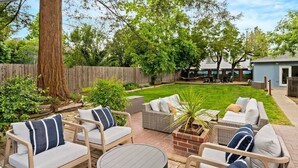 Un patio con mobiliario exterior, una mesa de ladrillo y césped.