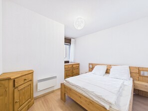 Une chambre à coucher avec un lit en bois, une table de chevet en bois, une commode en bois et un radiateur blanc.