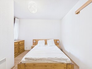 A small, single-bed room with a wooden headboard, a bedside table, and a wardrobe.
