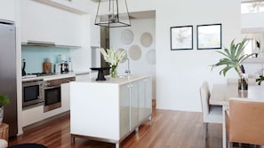 A modern kitchen with white cabinetry, a central island, and a dining area with a table and chairs.